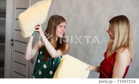 Two girl friends pillow fight in room Two girl friends pillow fight in room 73567258