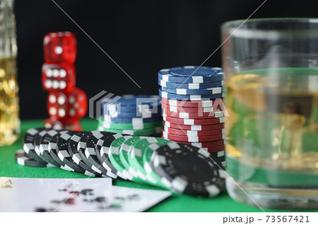 On table are chips for casino cards and glass of alcohol On table are chips for casino cards and glass of alcohol 73567421