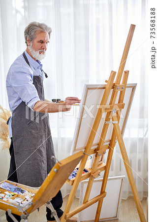 senior artist immersed in the creation of art 73568188