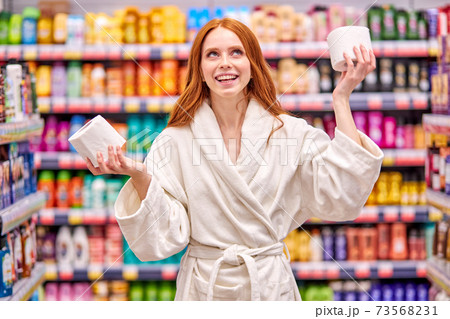 funny caucasian woman with red hair choosing the best toilet paper 73568231