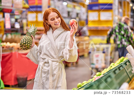 smiling female holding pineapple and apple in hands 73568233