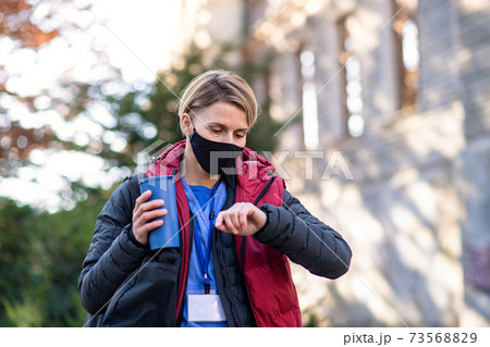 Woman caregiver, nurse or healthcare worker outdoors on the way to work, coronavirus concept. Woman caregiver, nurse or healthcare worker outdoors on the way to work, coronavirus concept. 73568829