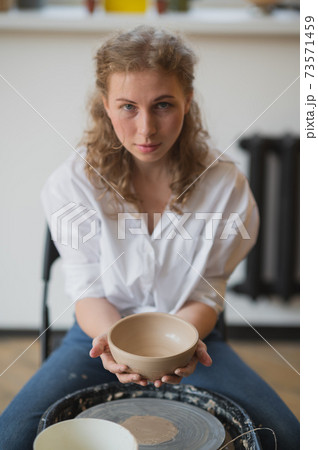 Job is done. Young female ceramist indoors with finished handmade clay product. Conception of pottery 73571459