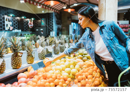 Young woman in denim jacket buys fruits Young woman in denim jacket buys fruits 73572157