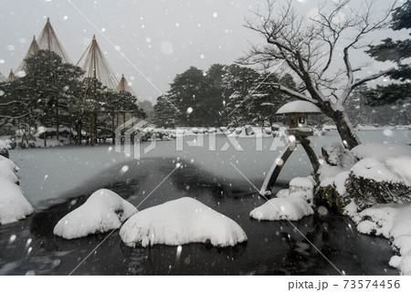 雪が舞う兼六園と雪吊り 73574456