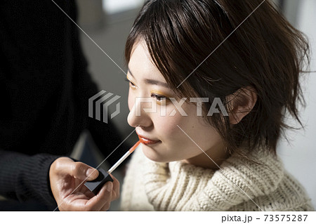 キュートなメイクをしてもらう女性 73575287