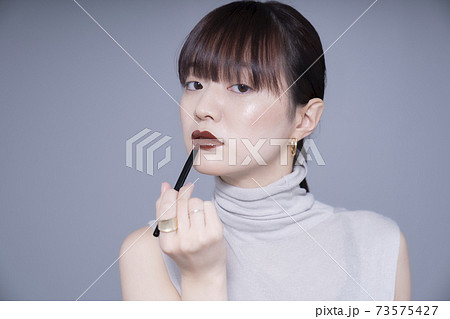 ブラウンリップを塗る女性 73575427