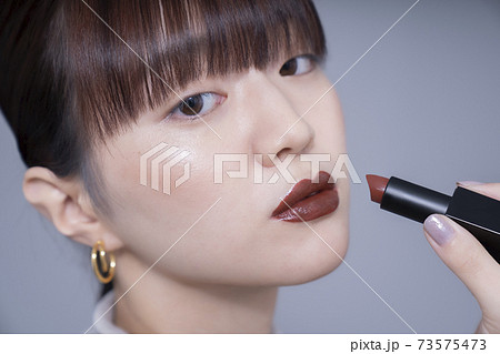 ブラウンリップを塗る女性 73575473