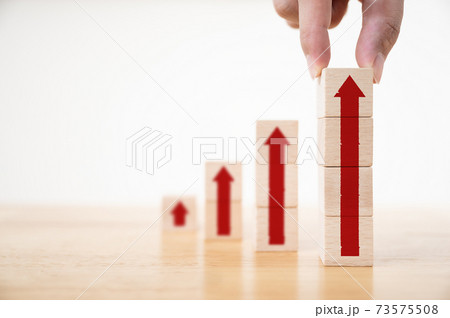 Hand arranging wood block stacking as step stair with arrow up 73575508