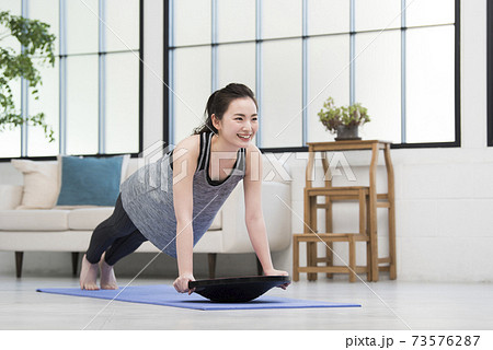 若い女性 ホームトレーニング バランスボード 若い女性 ホームトレーニング バランスボード 73576287