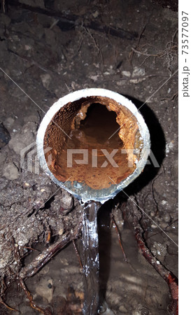 Old broken rusty water pipe underground with running water during out 73577097