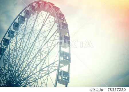 Under view of ferris wheel for background with copy space. Toned photo with sun lens flare. Under view of ferris wheel for background with copy space. Toned photo with sun lens flare. 73577220
