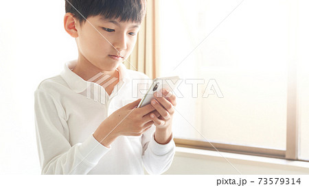 スマホの画面を見つめている男の子 73579314