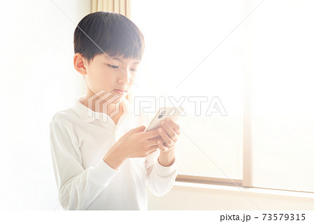 スマホの画面を見つめている男の子 スマホの画面を見つめている男の子 73579315