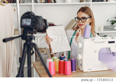 Woman sitting in studio and sew cloth Woman sitting in studio and sew cloth 73580313