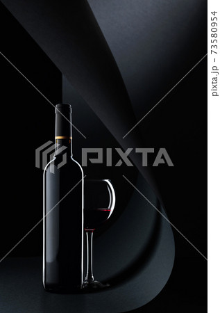Bottle and glass of red wine on a black background. 73580954