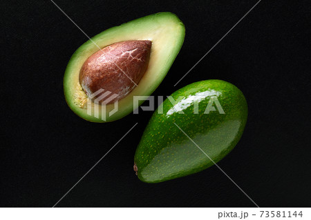 Macro shot of fresh avocados cut in a half on the black background Macro shot of fresh avocados cut in a half on the black background 73581144