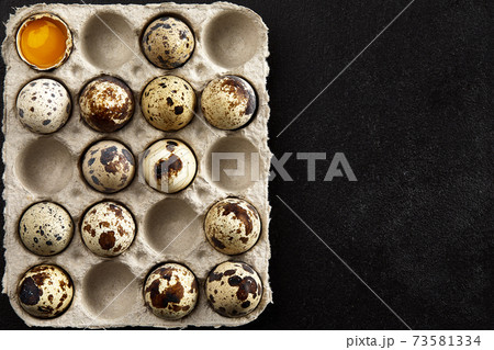 Quail eggs in the cardboard packing on the black table. Quail eggs in the cardboard packing on the black table. 73581334