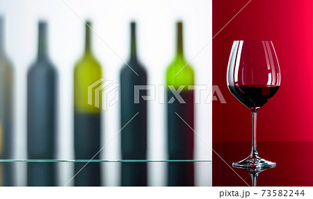 Bottles and glass of red wine on a black reflective background. 73582244