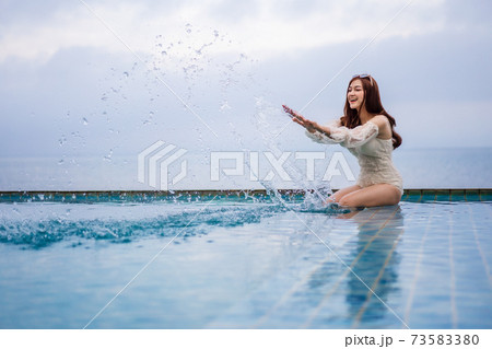 woman playing water splash in swimming pool with sea background 73583380