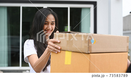 Young Asian woman customer receiving package from delivery man at home. 73583789