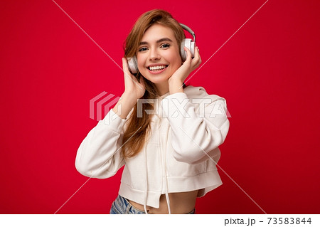 Photo of beautiful happy smiling young blonde woman wearing white hoodie isolated over colourful 73583844