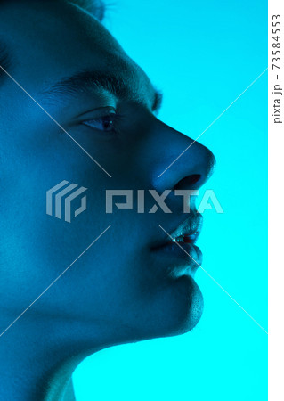 Handsome caucasian man's portrait isolated on blue studio background in neon light, monochrome Handsome caucasian man's portrait isolated on blue studio background in neon light, monochrome 73584553