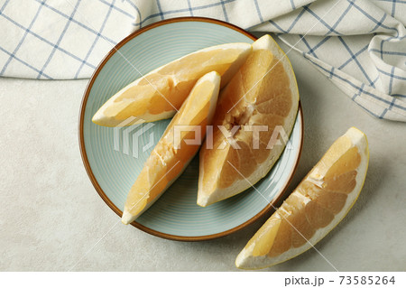 Kitchen towel and plate with pomelo slices on white textured background 73585264