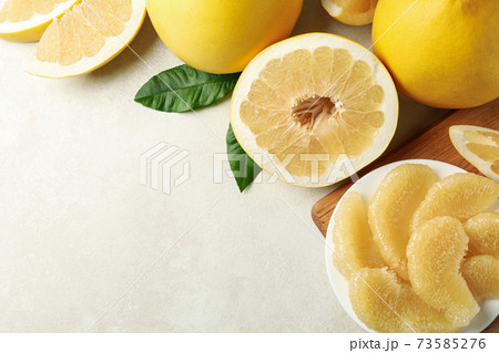 Ripe pomelo and plate with pomelo slices on white textured background 73585276