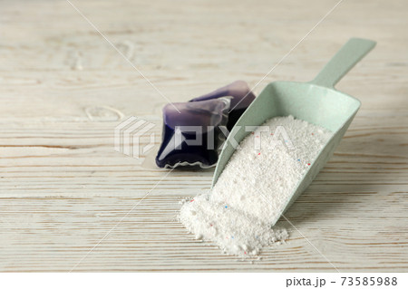 Scoop with washing powder and laundry capsules on white wooden background 73585988
