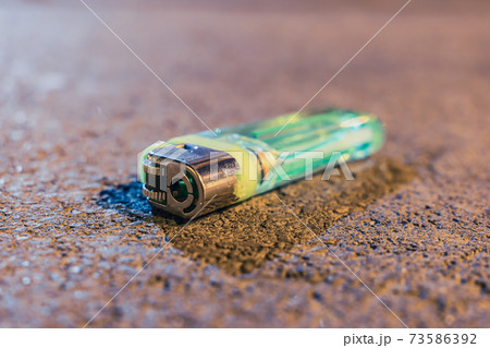 A used and discarded lighter lies on the road in the evening 73586392
