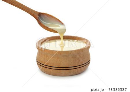 Spoon and bowl with condensed milk isolated on white background 73586527