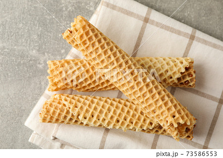 Napkin with wafer rolls with condensed milk on gray background 73586553
