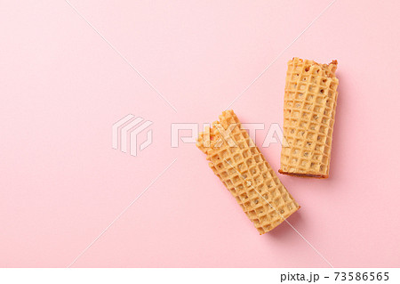 Tasty wafer rolls with condensed milk on pink background Tasty wafer rolls with condensed milk on pink background 73586565