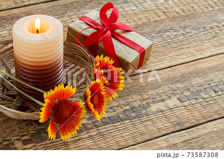 Gift box, candle and fresh flowers on wooden table. Gift box, candle and fresh flowers on wooden table. 73587308