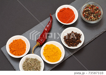 Various ground spices and herbs on stone cutting board. Various ground spices and herbs on stone cutting board. 73587310