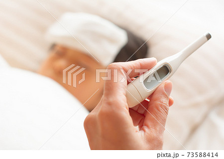 体調不良で寝込む子供と体温計 体調不良で寝込む子供と体温計 73588414