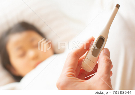 体調不良で寝込む子供と体温計 73588644