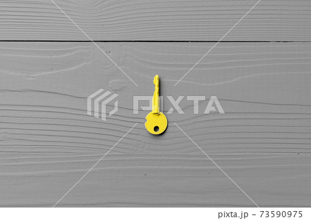 Yellow door key on gray wooden background 73590975
