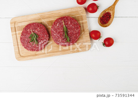 Two raw beef burger patties on wooden board Two raw beef burger patties on wooden board 73591344
