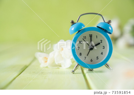 Spring time daylight saving concept - with alarm clock and flowers 73591854