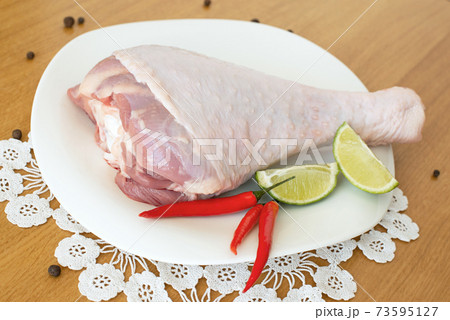 aw leg of turkey cutting board with limes and parsley on a white background, isolate.. 73595127