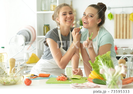 Portrait of beautiful teenagers cooking in kitchen Portrait of beautiful teenagers cooking in kitchen 73595333