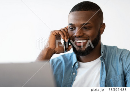 Closeup Portrait Of Smiling Black Man Talking On Cellphone And Using Laptop 73595483