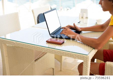 Workplace in a cafe with a sea view. Man working on a laptop in a cafe. Copy space. Mock up. Workplace in a cafe with a sea view. Man working on a laptop in a cafe. Copy space. Mock up. 73596281