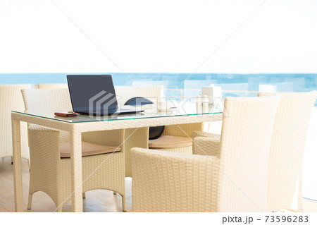 Workplace in a cafe with a sea view. Man working on a laptop in a cafe. Copy space. Mock up. 73596283