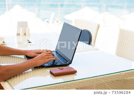 Workplace in a cafe with a sea view. Man working on a laptop in a cafe. Copy space. Mock up. Workplace in a cafe with a sea view. Man working on a laptop in a cafe. Copy space. Mock up. 73596284
