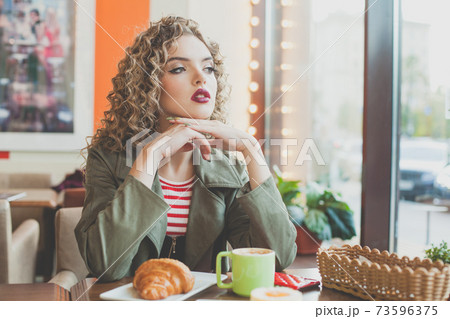 Romantic woman drinking coffee and looking out the window in cafe 73596375