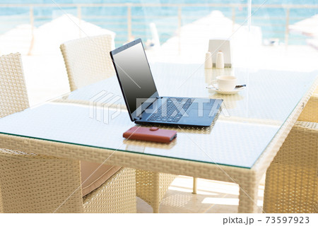 Workplace in a cafe with a sea view. Man working on a laptop in a cafe. Copy space. Mock up. Workplace in a cafe with a sea view. Man working on a laptop in a cafe. Copy space. Mock up. 73597923