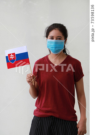 Masked woman in brown shirt and Slovakia flag in hand. 73598136
